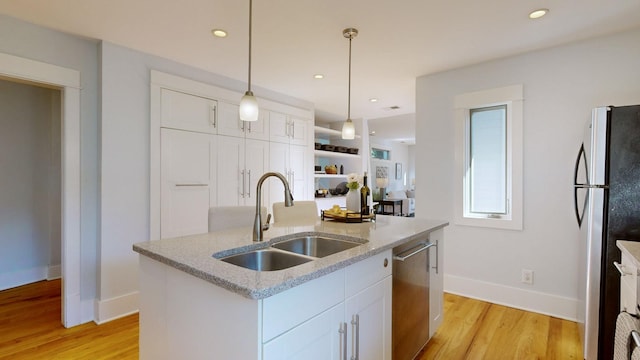 kitchen featuring sink, stainless steel appliances, decorative light fixtures, a center island with sink, and white cabinets