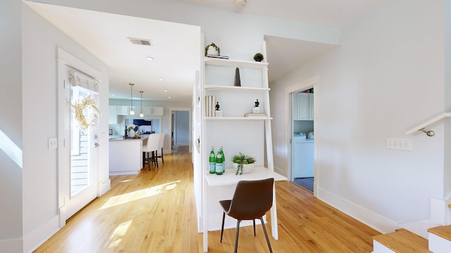 corridor featuring washer and dryer and light hardwood / wood-style floors