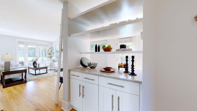 bar with white cabinets and light wood-type flooring