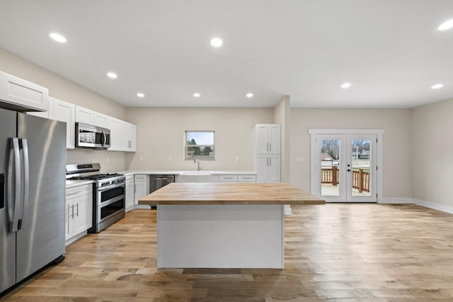 kitchen with french doors, wood counters, plenty of natural light, white cabinets, and appliances with stainless steel finishes