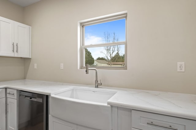 kitchen featuring dishwasher, sink, white cabinetry, and light stone counters