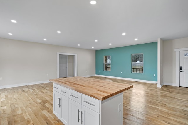 kitchen featuring wooden counters, white cabinets, a kitchen island, and light hardwood / wood-style floors