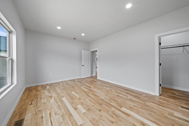 unfurnished bedroom with a closet, light hardwood / wood-style flooring, and multiple windows