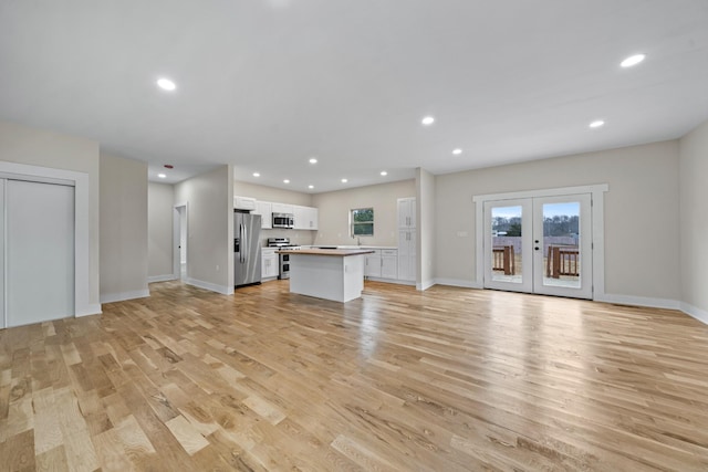 unfurnished living room with french doors and light wood-type flooring