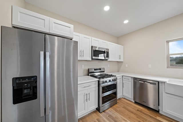 kitchen with white cabinetry, light hardwood / wood-style flooring, and stainless steel appliances