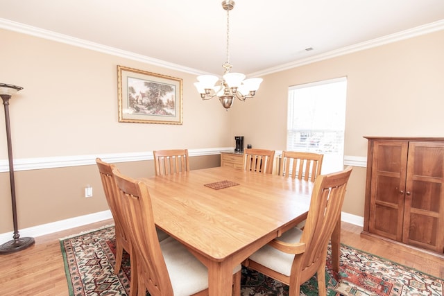 dining space with crown molding, light hardwood / wood-style floors, and an inviting chandelier