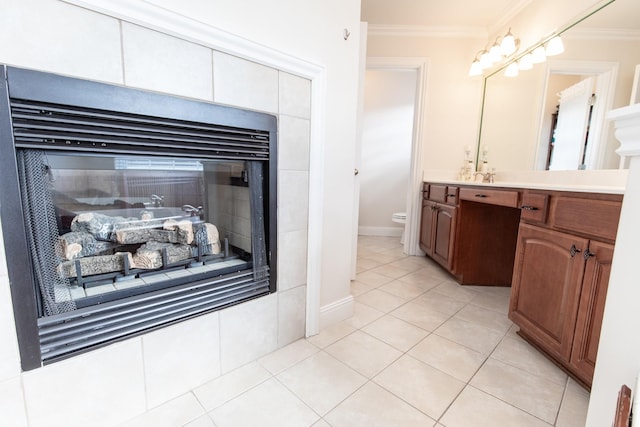 bathroom with tile patterned floors, ornamental molding, vanity, toilet, and a tiled fireplace