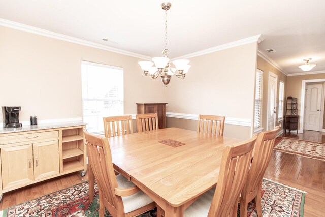 dining area featuring a chandelier, light wood-type flooring, and ornamental molding