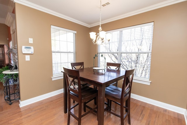 dining room with light hardwood / wood-style floors, a healthy amount of sunlight, and ornamental molding