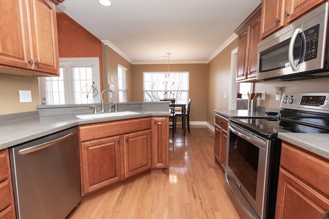 kitchen with pendant lighting, sink, light wood-type flooring, appliances with stainless steel finishes, and a notable chandelier