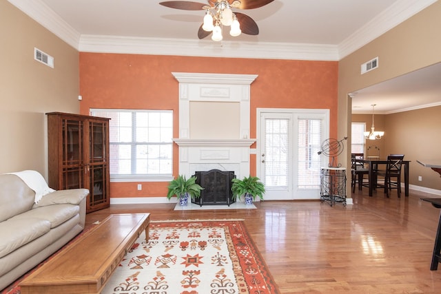 living room with a high end fireplace, hardwood / wood-style floors, ceiling fan with notable chandelier, and ornamental molding