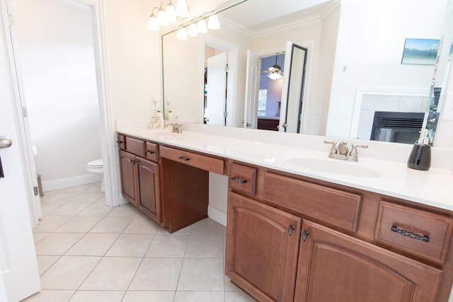 bathroom with vanity, a tile fireplace, tile patterned floors, toilet, and ornamental molding