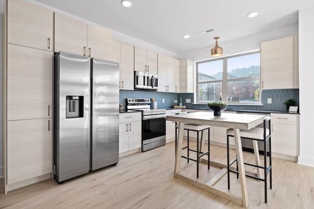 kitchen with stainless steel appliances, light hardwood / wood-style flooring, and tasteful backsplash