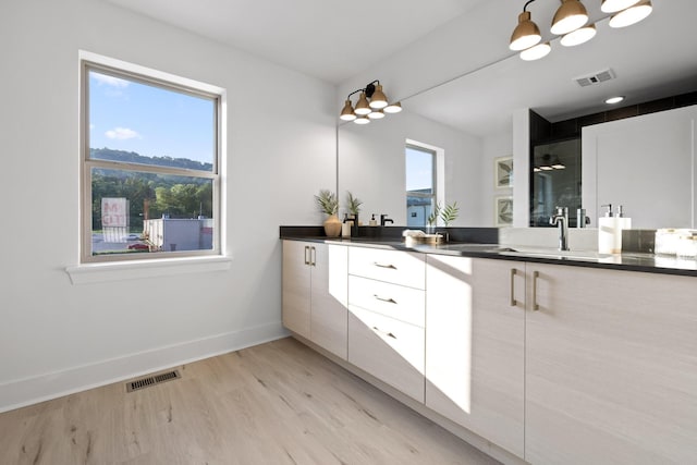 bathroom featuring hardwood / wood-style floors, vanity, a healthy amount of sunlight, and a shower with shower door