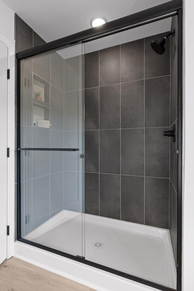 bathroom with hardwood / wood-style floors and a shower with shower door