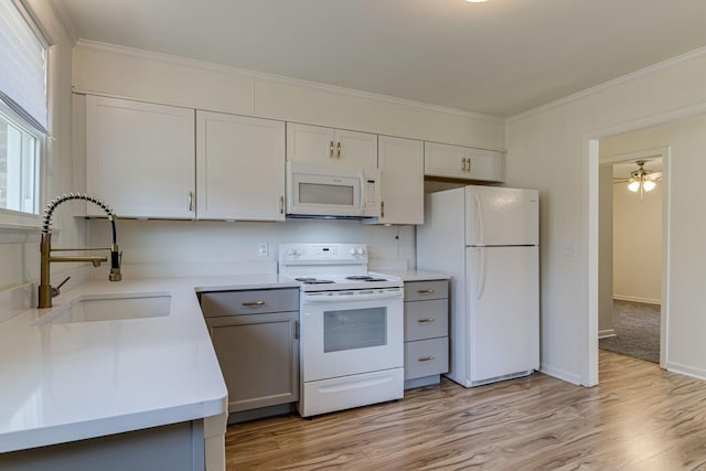 kitchen with white appliances, white cabinets, crown molding, sink, and light hardwood / wood-style flooring