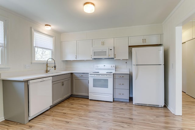 kitchen with gray cabinets, white appliances, sink, and light hardwood / wood-style flooring