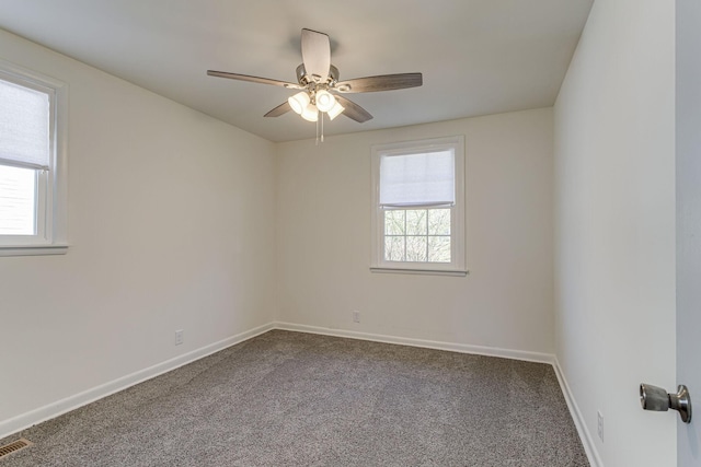 carpeted spare room featuring plenty of natural light and ceiling fan