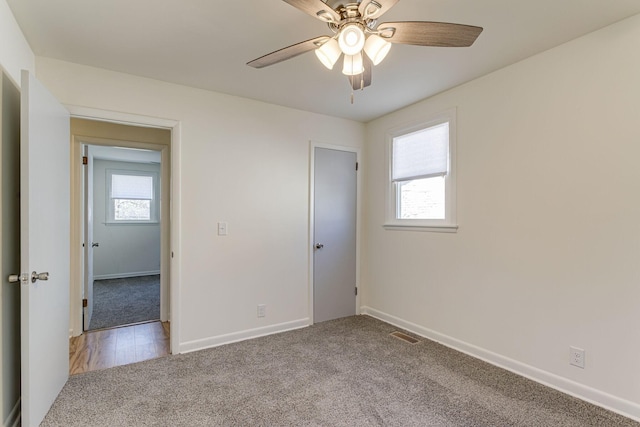 unfurnished room with ceiling fan, a healthy amount of sunlight, and light carpet