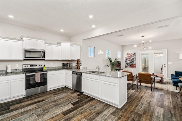 kitchen featuring kitchen peninsula, an inviting chandelier, white cabinetry, a textured ceiling, and stainless steel appliances