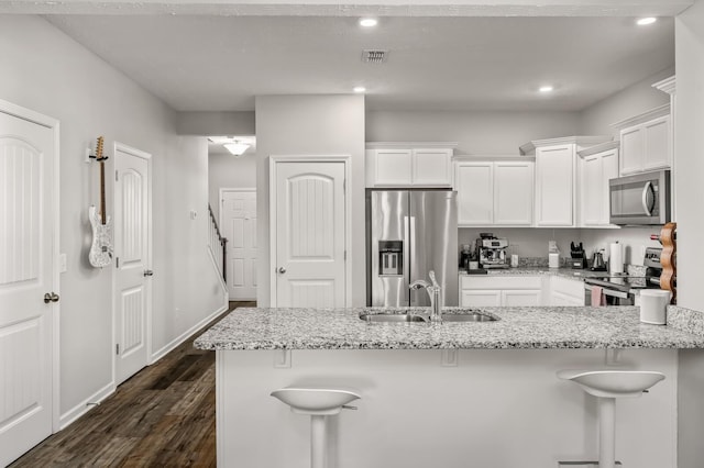 kitchen featuring sink, a kitchen breakfast bar, stainless steel appliances, and white cabinetry