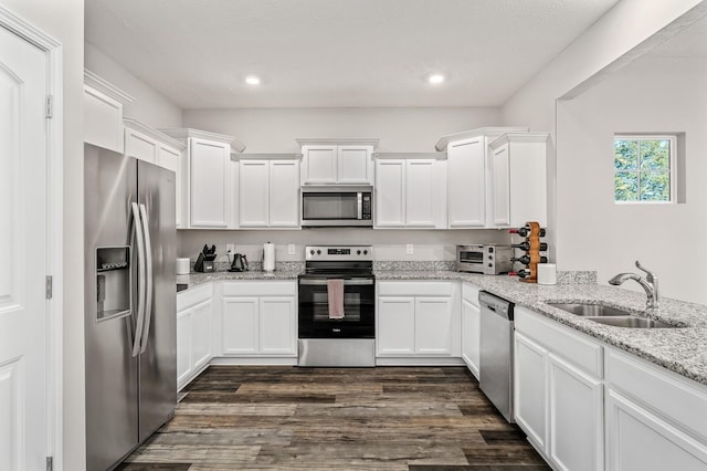 kitchen with light stone countertops, stainless steel appliances, white cabinets, and sink