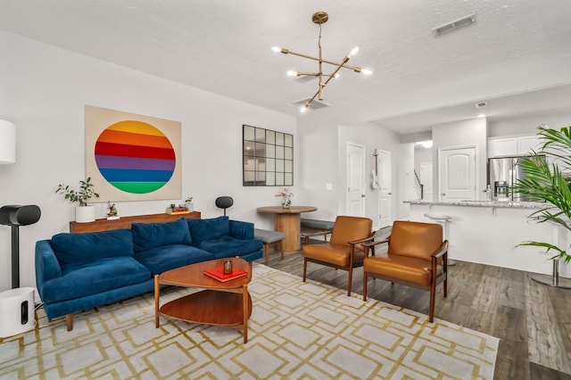 living room with a textured ceiling, an inviting chandelier, and light hardwood / wood-style flooring