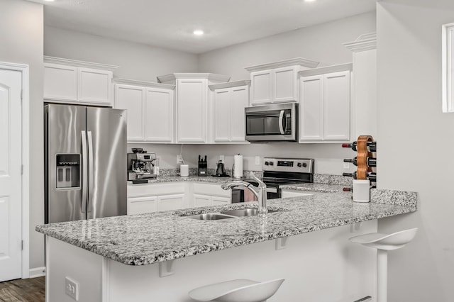 kitchen with a breakfast bar, white cabinets, and stainless steel appliances