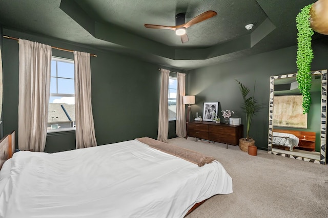 bedroom featuring ceiling fan, a tray ceiling, and carpet flooring