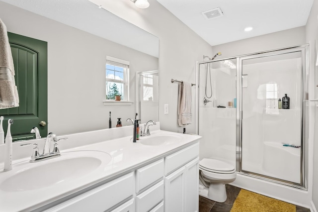 bathroom featuring toilet, a shower with shower door, and vanity