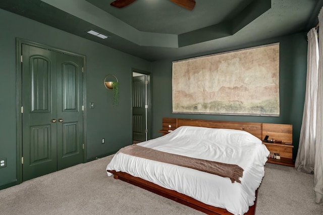 bedroom with ceiling fan, a closet, a raised ceiling, and carpet floors