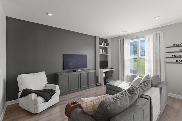 living room with built in shelves and light hardwood / wood-style floors