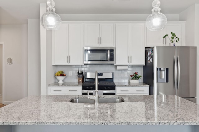 kitchen with a kitchen island with sink, decorative light fixtures, stainless steel appliances, and white cabinets