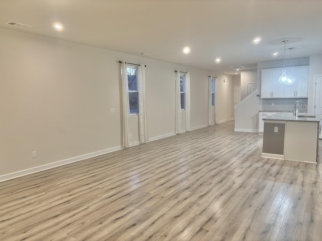 unfurnished living room with sink and light hardwood / wood-style flooring