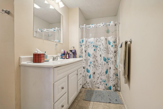 bathroom with a textured ceiling, vanity, and curtained shower