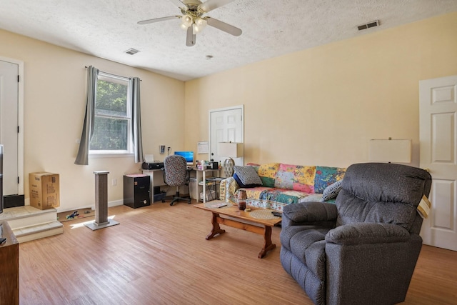 living room featuring a textured ceiling, light hardwood / wood-style flooring, and ceiling fan