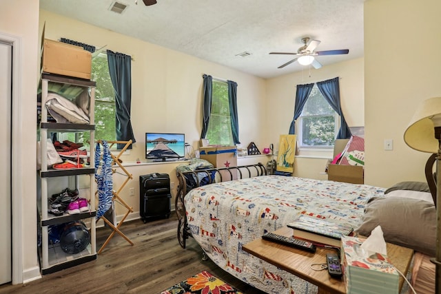 bedroom featuring ceiling fan, dark hardwood / wood-style flooring, and a textured ceiling