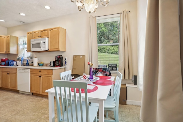 kitchen featuring light brown cabinets, white appliances, and an inviting chandelier