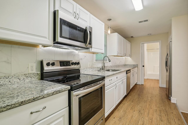 kitchen featuring white cabinets, appliances with stainless steel finishes, decorative light fixtures, and sink