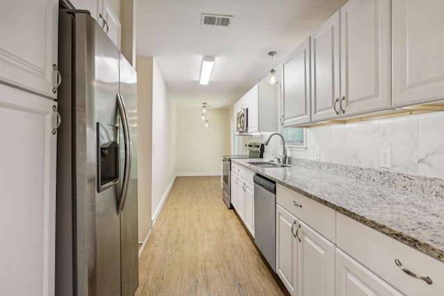 kitchen featuring white cabinets, pendant lighting, sink, and appliances with stainless steel finishes