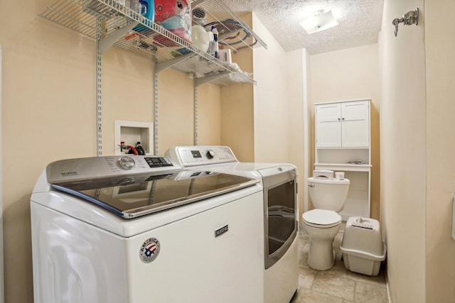 washroom with a textured ceiling and washing machine and clothes dryer