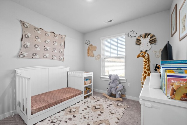 carpeted bedroom featuring a nursery area