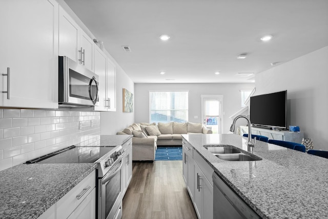 kitchen with light stone counters, sink, white cabinets, and stainless steel appliances