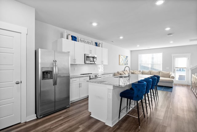 kitchen featuring appliances with stainless steel finishes, a kitchen breakfast bar, a kitchen island with sink, sink, and white cabinets