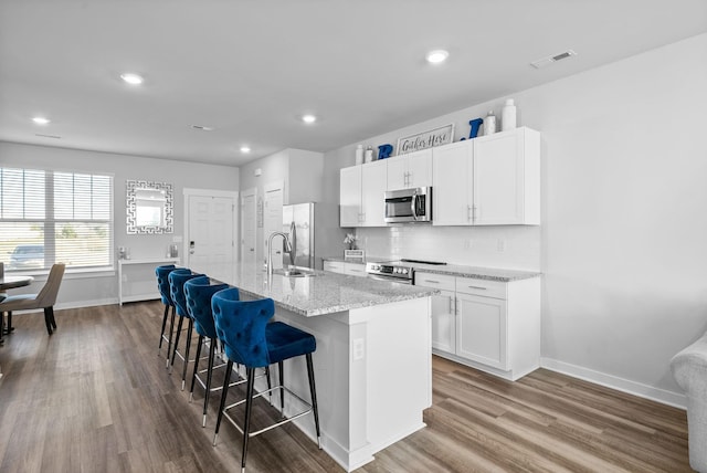 kitchen featuring a center island with sink, a kitchen breakfast bar, white cabinets, sink, and stainless steel appliances