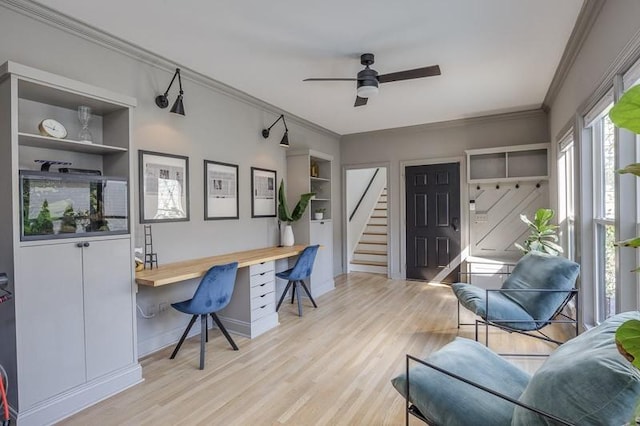 office area with built in shelves, ceiling fan, crown molding, built in desk, and light wood-type flooring