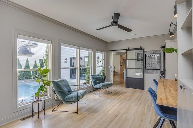 interior space with wood-type flooring, a barn door, ceiling fan, and crown molding