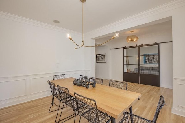 dining area featuring a notable chandelier, light hardwood / wood-style floors, and ornamental molding