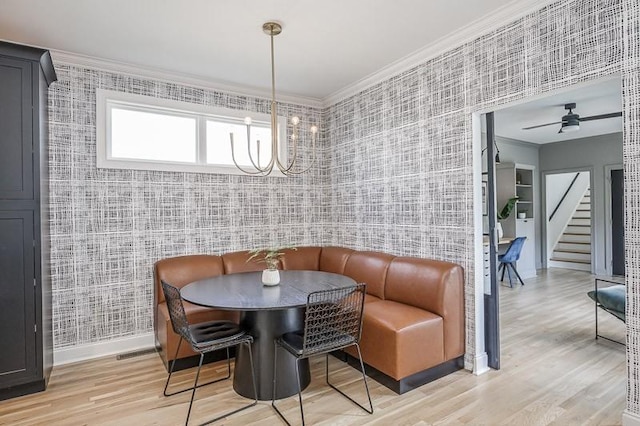 dining space featuring hardwood / wood-style floors, ceiling fan with notable chandelier, breakfast area, and crown molding