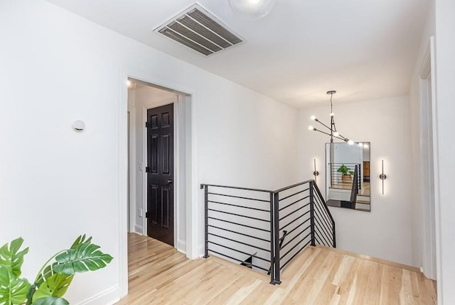 staircase with hardwood / wood-style floors and an inviting chandelier